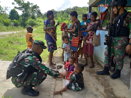Berbagi dalam Keterbatasan, Satgas Yonif 126KC Membagikan Biskuit buat Anak-anak 